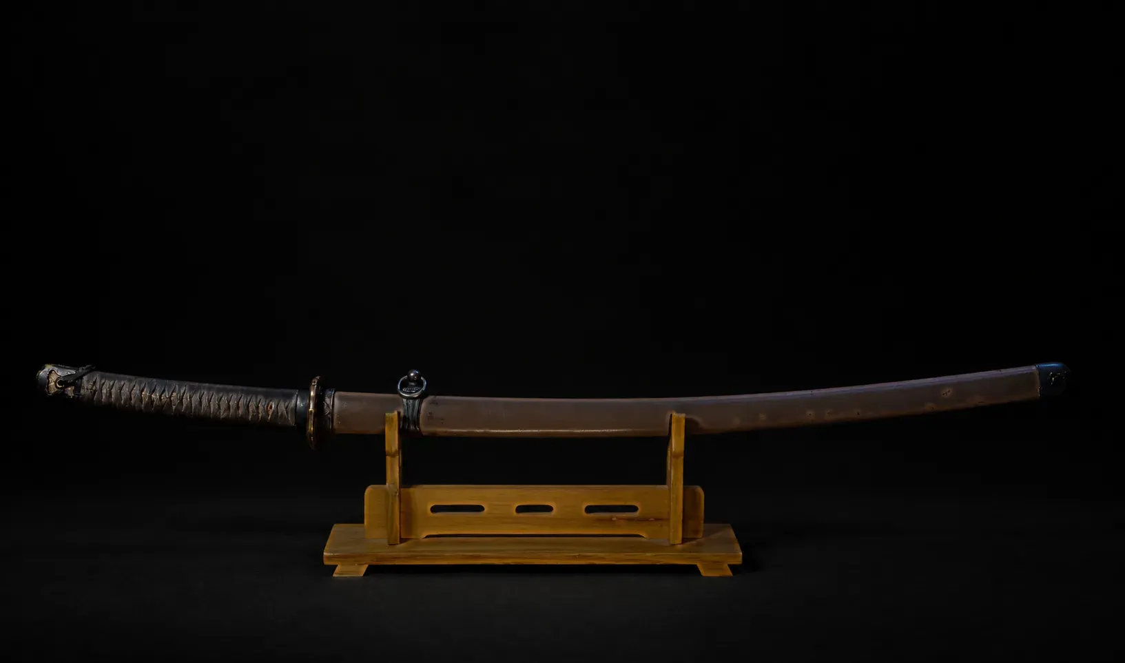 The Type 3 guntō mounted in its steel saya, displayed on a stand