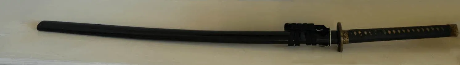 The sword in its black-lacquer mounting with a cherry-blossom tsuba and hilt fittings