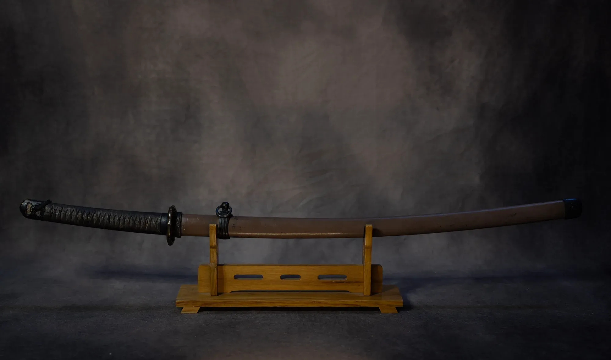 The Type 3 guntō mounted in its steel saya, displayed on a stand