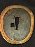 Central kaiguntō tsuba reverse showing gilt brass rim and dark field with hitsu-ana