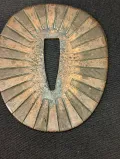 Rayed seppa close-up showing sunburst radial pattern in brass with green patina