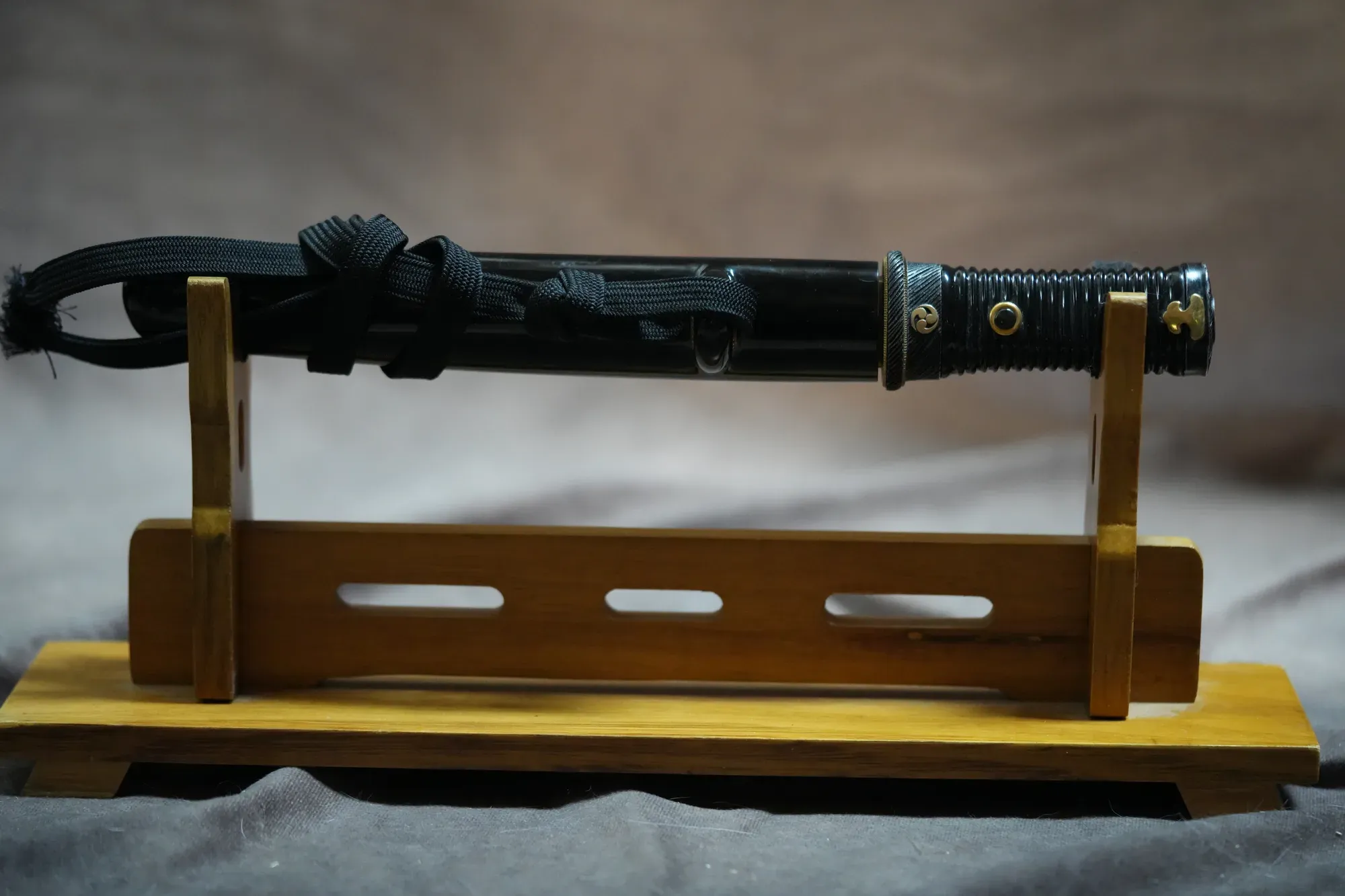 Shōwa-era tantō mounted in black-lacquer aikuchi koshirae, displayed on a stand