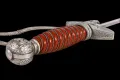 The orange spiral-fluted grip and oakleaf pommel close up, with the bullion troddel cord looped around it