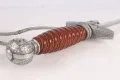 The orange spiral-fluted grip and oakleaf pommel close up, with the bullion troddel cord looped around it