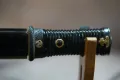 The tantō grip showing the brass mitsudomoe (triple-comma) fuchi, menuki and kashira