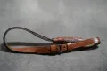 The reproduction leather tassel with its strap and buckle