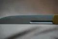 The tantō blade partly drawn, showing a groove and a shallow curvature