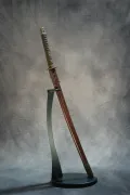 The complete koshirae displayed upright on a stand — same-wrapped tsuka, brass fuchi, and brown leather saya cover
