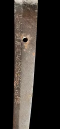 The nakago held upright with the machi at the top, showing the eleven-character signature reading down the tang and the single mekugi-ana