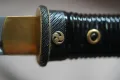 Brass mitsudomoe (triple-comma) menuki on the ribbed black grip
