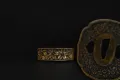 The gilt cherry-blossom collar (fuchi) beside the matching cherry-blossom tsuba
