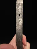 The nakago held in the hand, the signature side, showing the patina around the strokes
