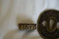 The gilt cherry-blossom collar (fuchi) beside the matching cherry-blossom tsuba