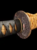 The reverse of the dragon tsuba over its seppa, showing the plugged hitsu-ana, with the sageo looped behind