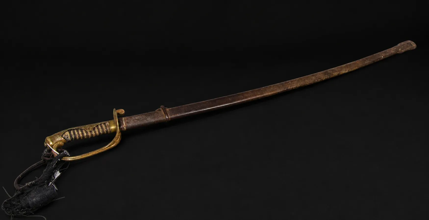 The complete sabre in its scabbard, the black sword tassel hanging from the knuckle bow