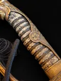 The grip close up, showing the cherry-blossom rosette and the stippled ground beneath the gilt mounts