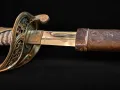 The pierced brass guard with the blade at the scabbard throat