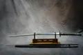 The bare blade displayed on a stand with its black scabbard