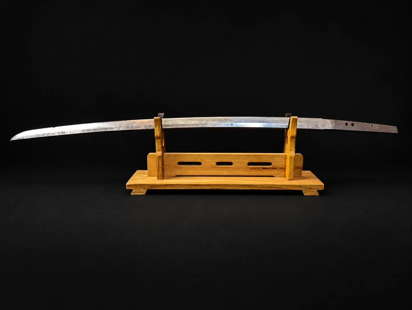 The bare blade resting on a wooden stand, showing its full profile and curvature